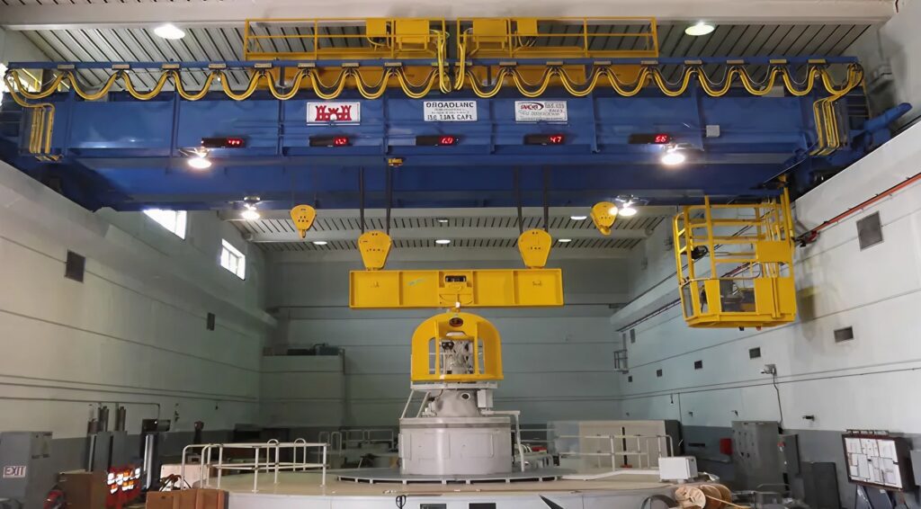Blue overhead double girder crane with yellow hoists in industrial facility.